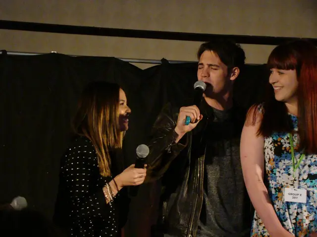 This picture shows three people standing and two people speaking with the help of a microphone