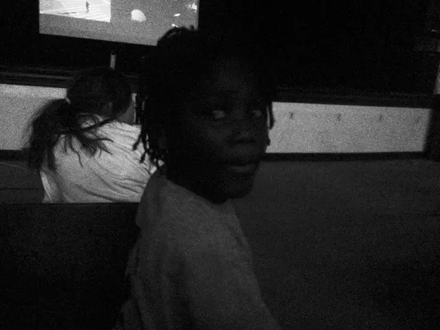 In this picture we can see few people, television and dark background.